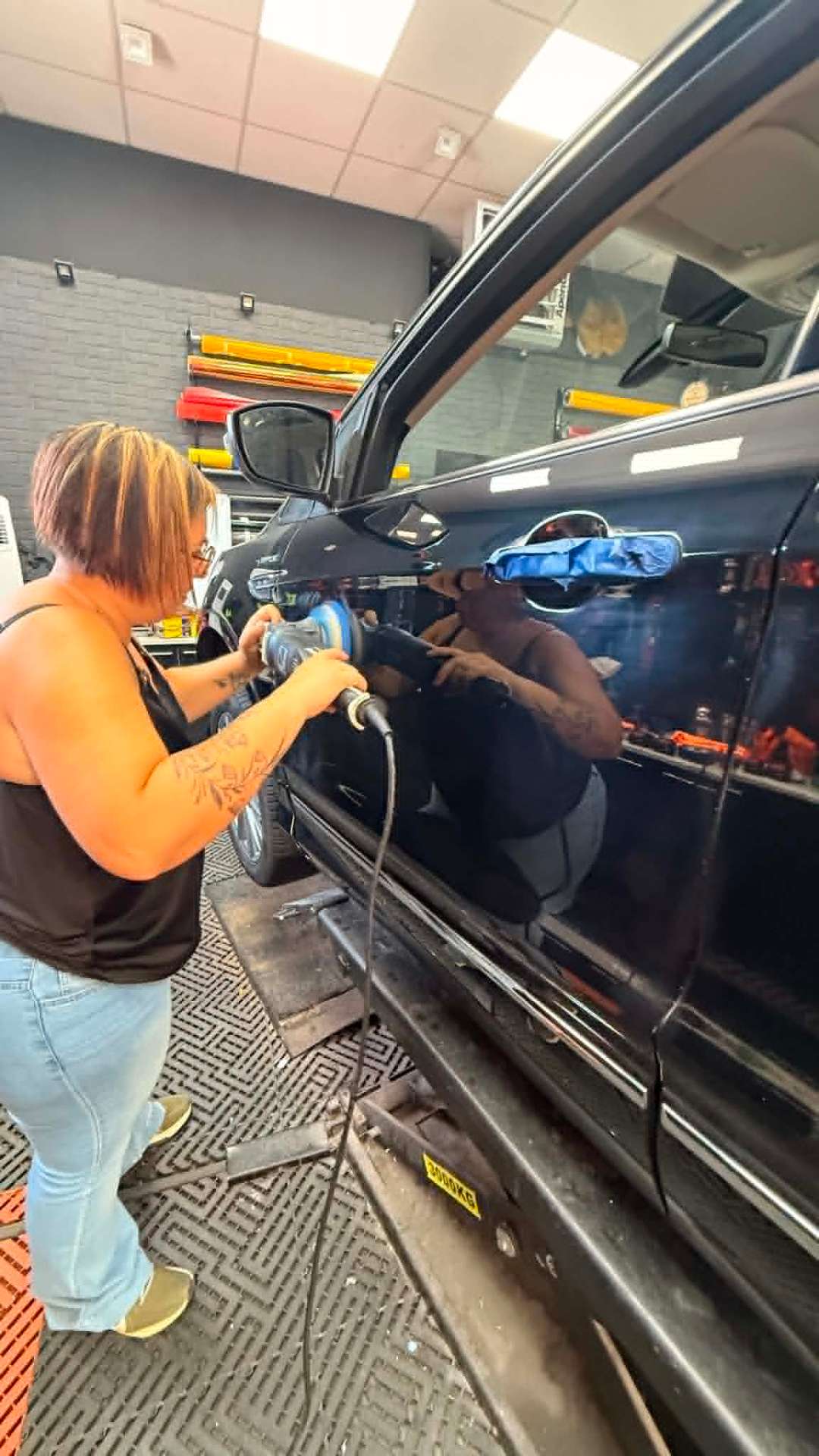 Stagiaire Emilie en polissage sur portière voiture noire formation polissage niveau 1
